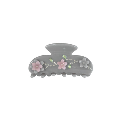 Gray hair claw clip with floral decoration and rhinestone embellish on a white background