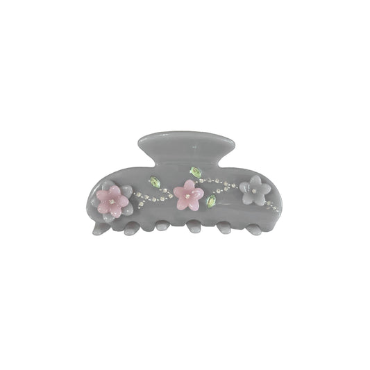 Gray hair claw clip with floral decoration and rhinestone embellish on a white background