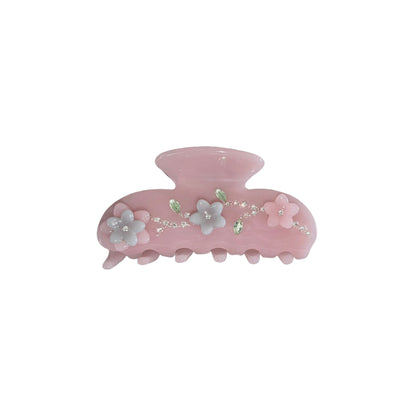 Pink hair claw clip with floral decoration and rhinestone embellish on a white background