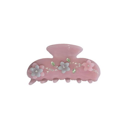 Pink hair claw clip with floral details, gemstones, and crystal embellishments on a white background.